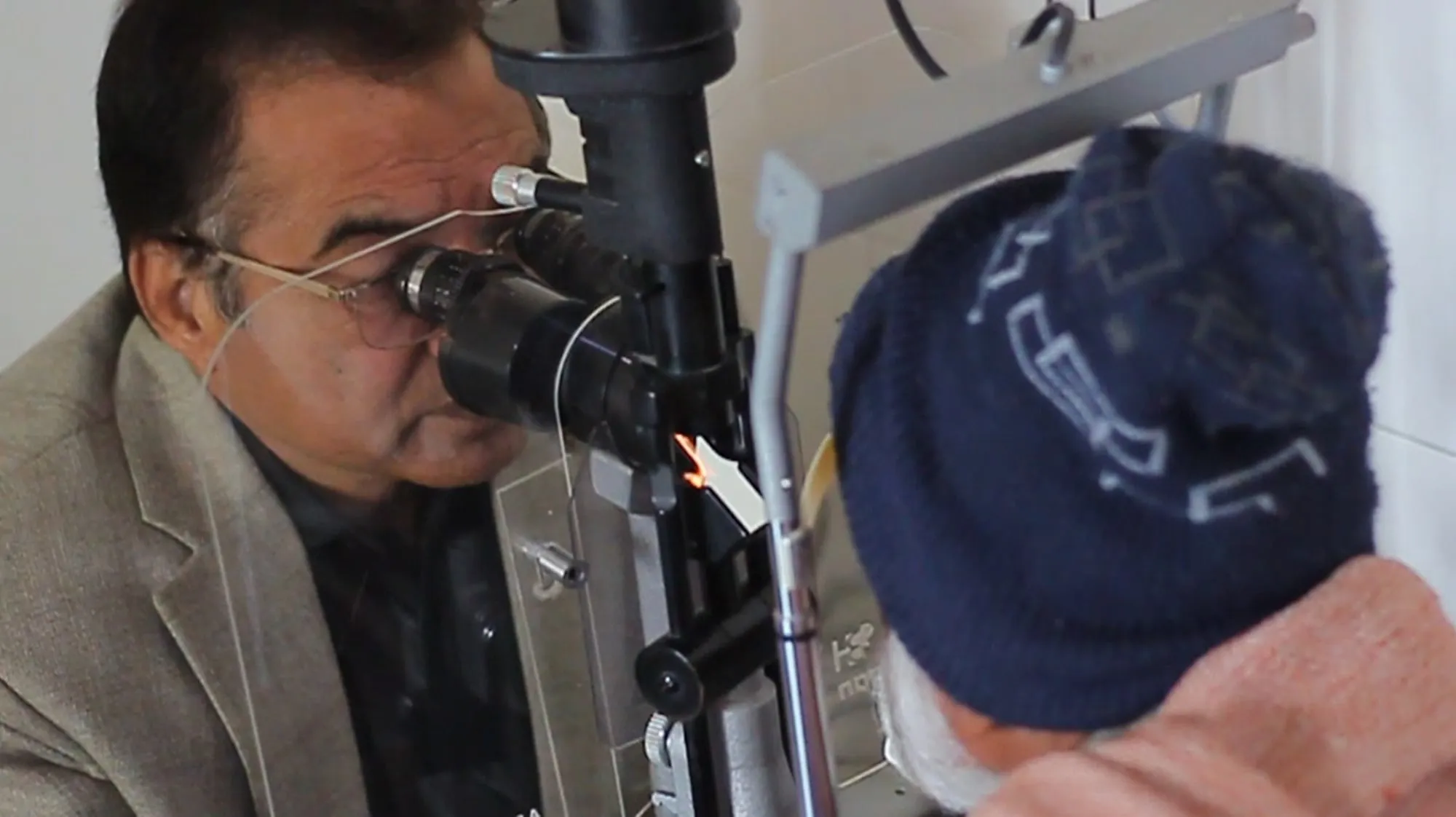 A doctor examines a patient's eyes with a slit lamp